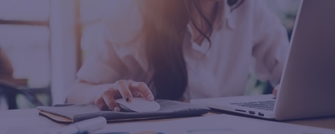 Person using a mouse and laptop in office setting